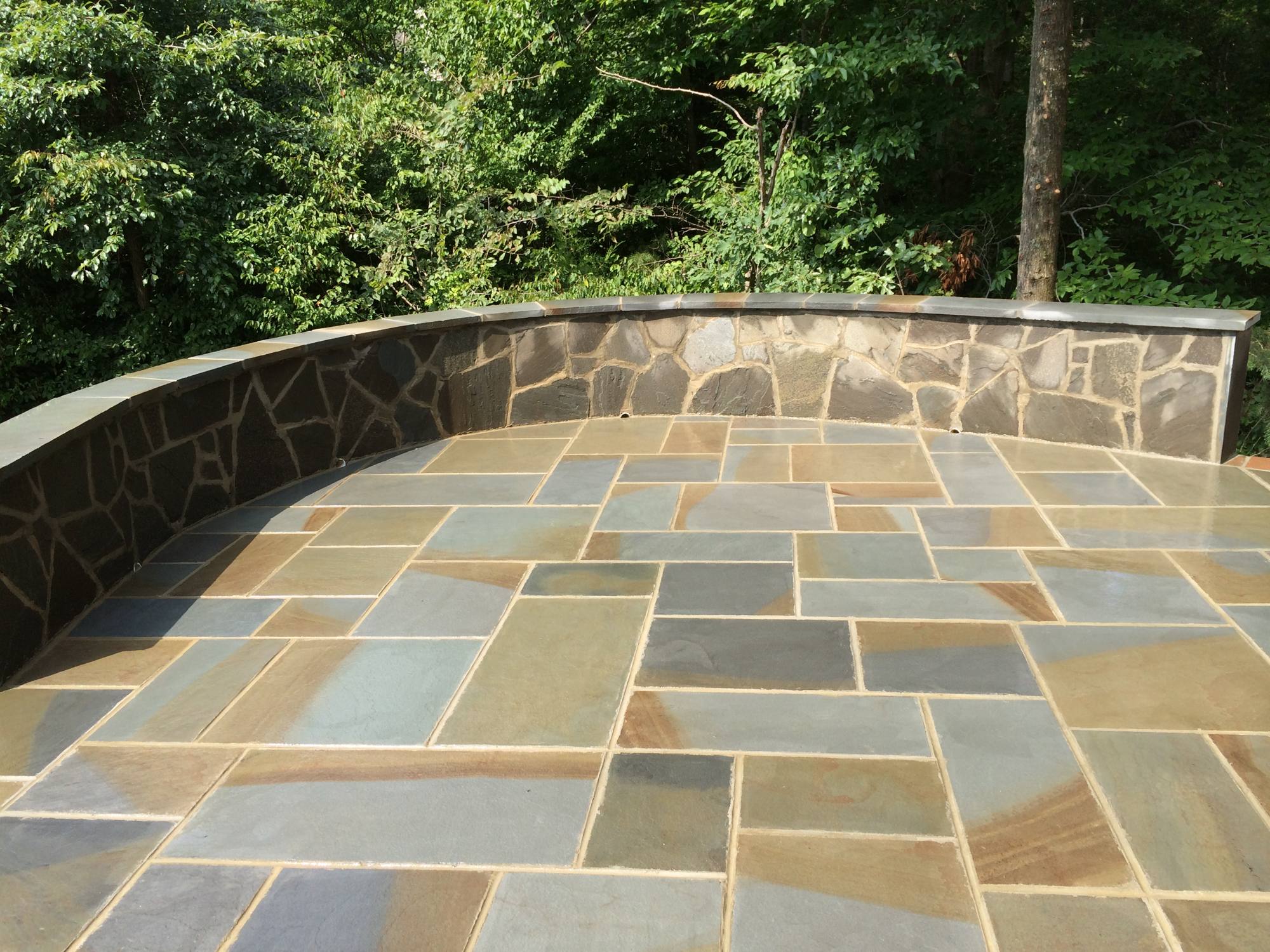Full-color bluestone patio with curved stone veneer sitting wall in Northern Virginia