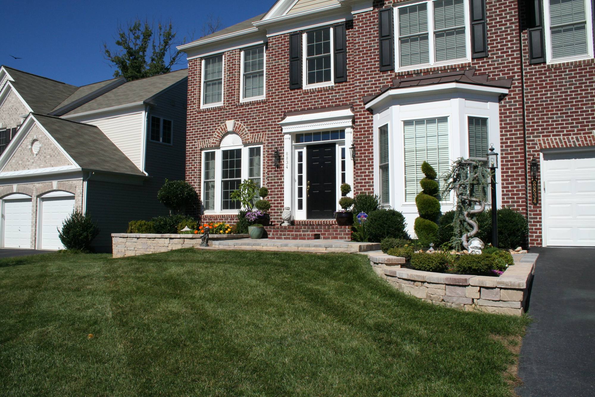 Brick colonial with stone front-yard walls and landscaping in Northern Virginia