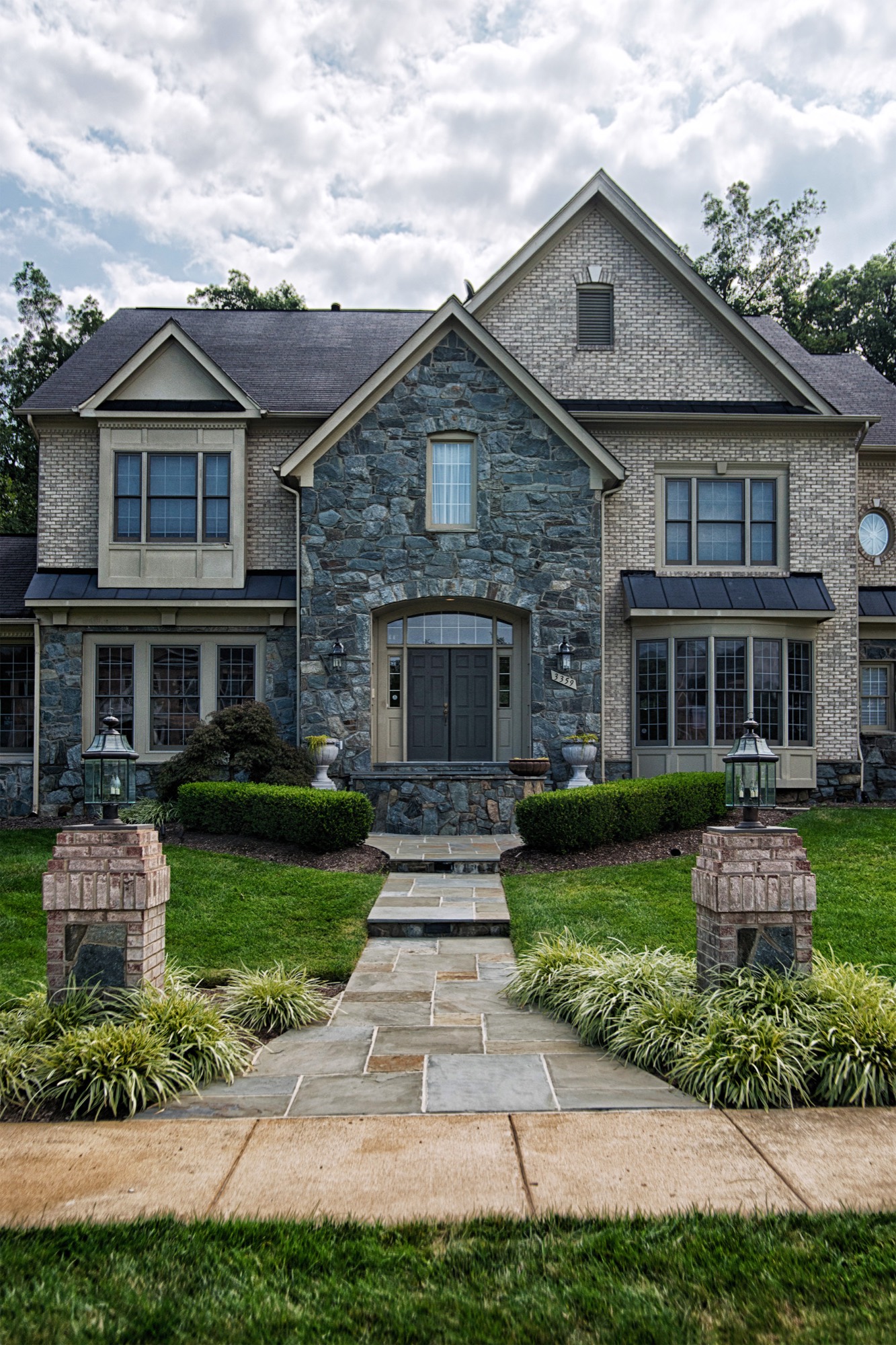 Flagstone front walkway with brick column entrance to a stone home in Northern Virginia