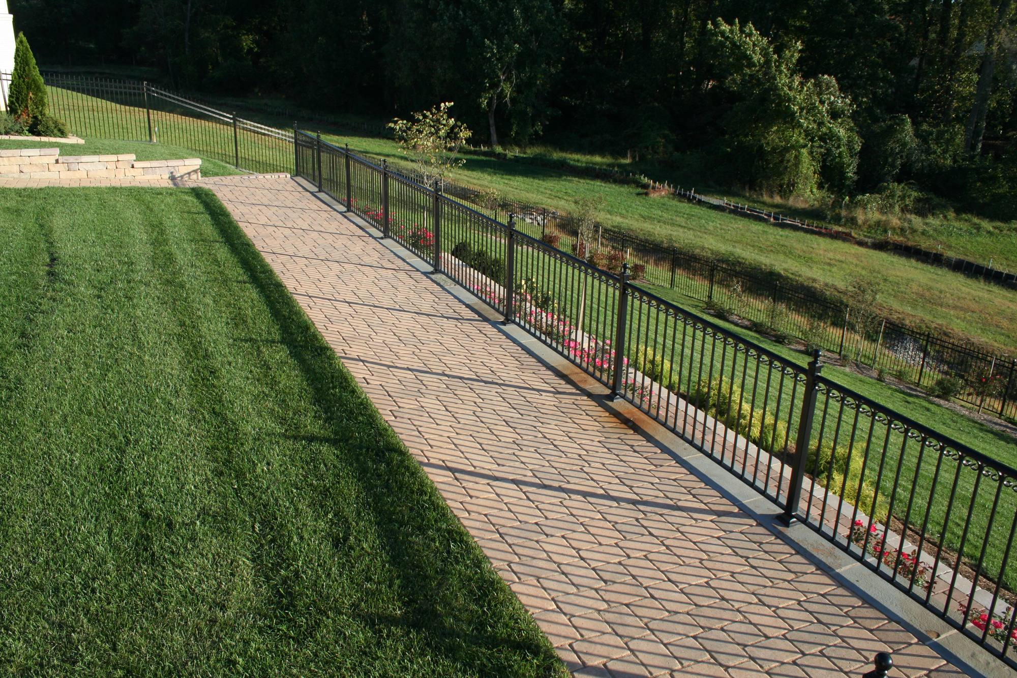 Long paver walkway beside an iron fence and lawn in Northern Virginia